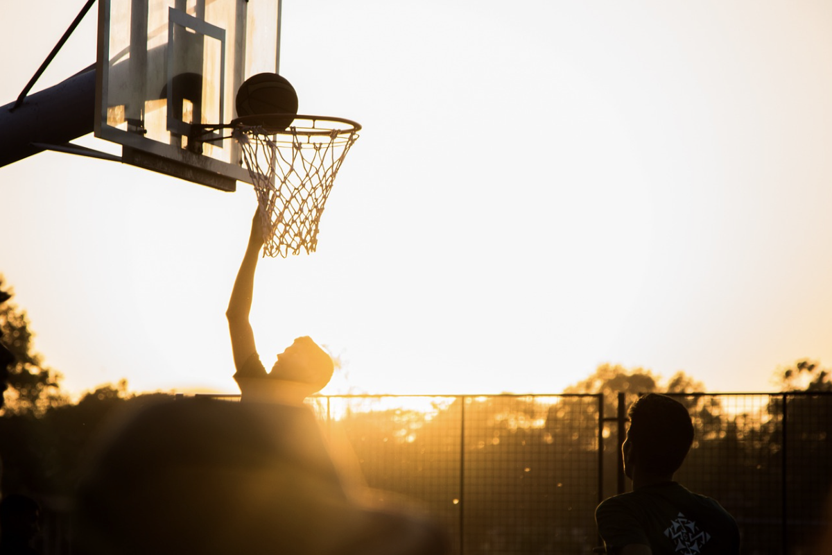 To personer spiller basketball i solnedgang